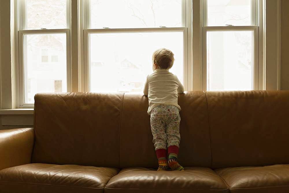 Caucasian boy looking out living room window