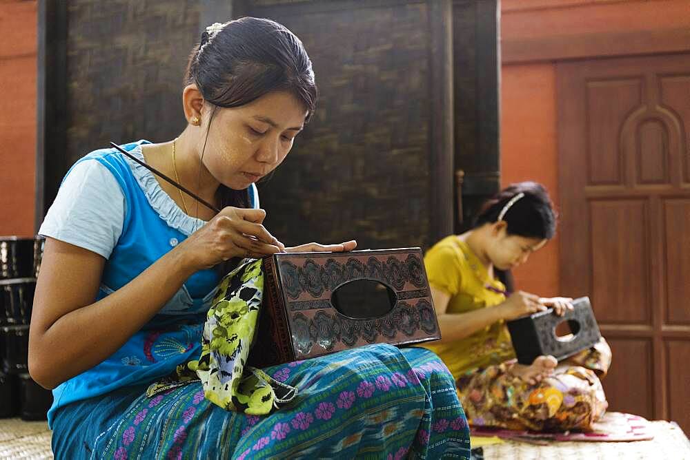 Asian artisans carving traditional design in workshop