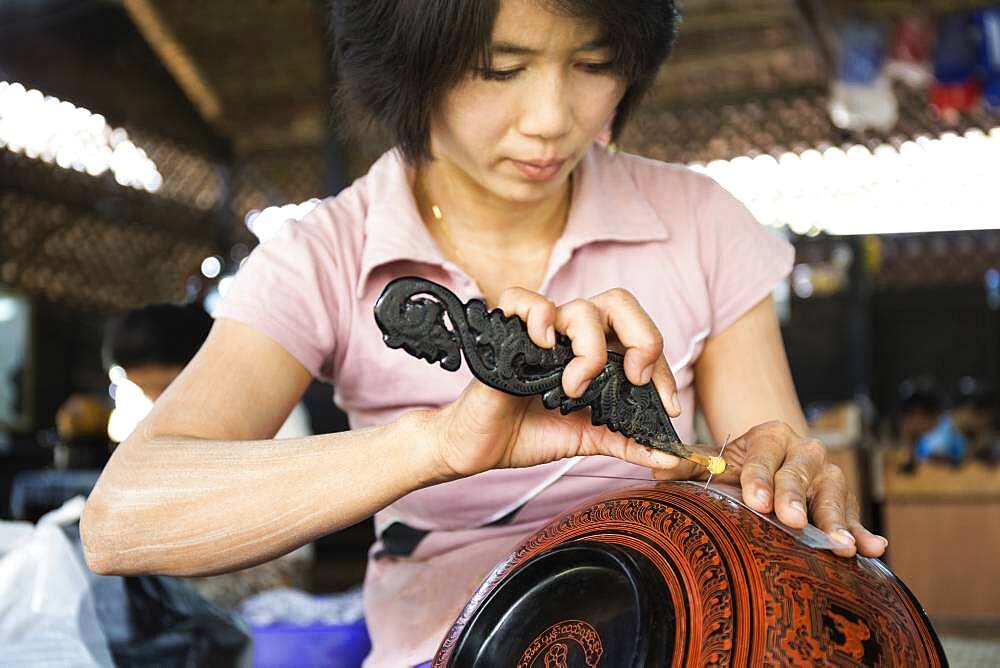 Asian artisan carving traditional design in workshop