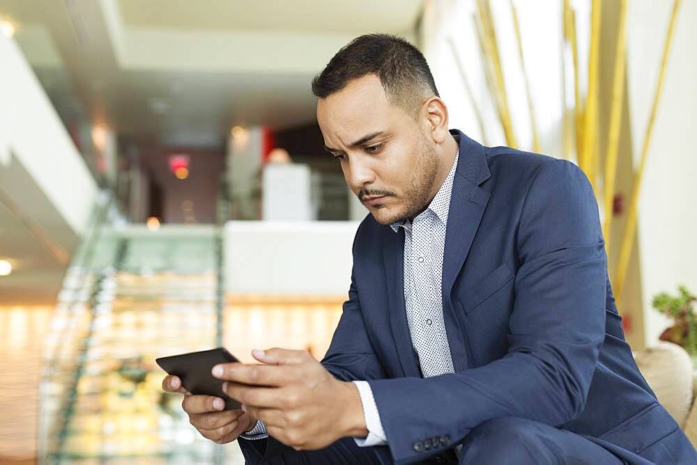 Hispanic businessman using digital tablet in hotel lobby