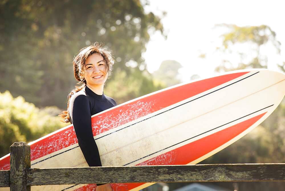 Woman carrying surfboard outdoors