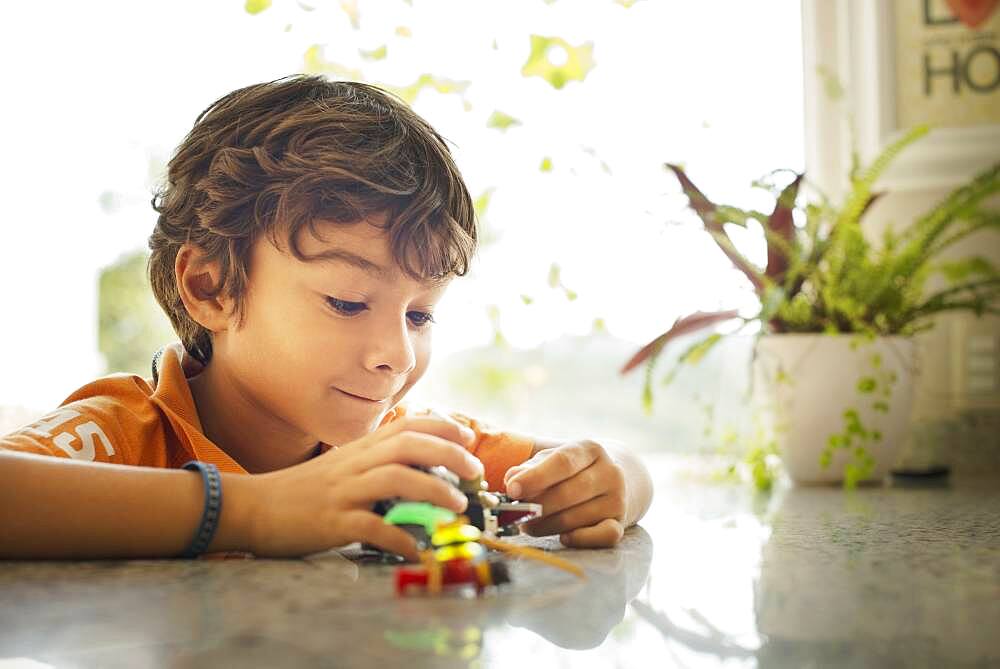 Hispanic boy playing with toy cars on counter