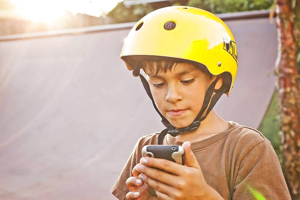 Mixed race boy in helmet using cell phone