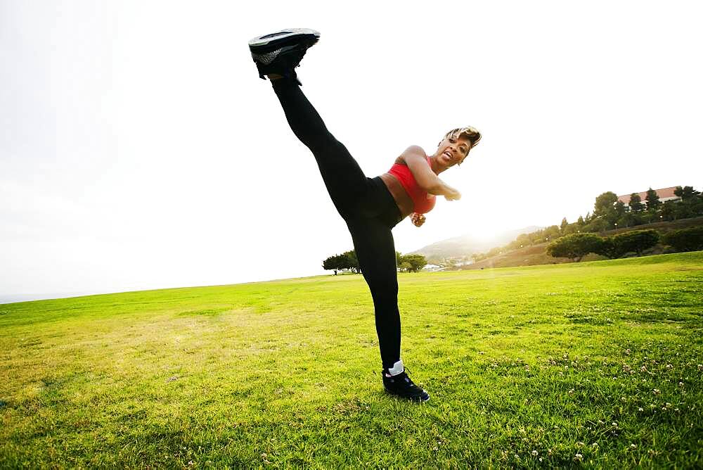 Black woman kick boxing in field