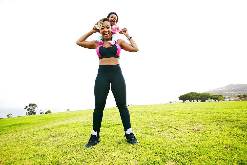 Black woman holding daughter in field