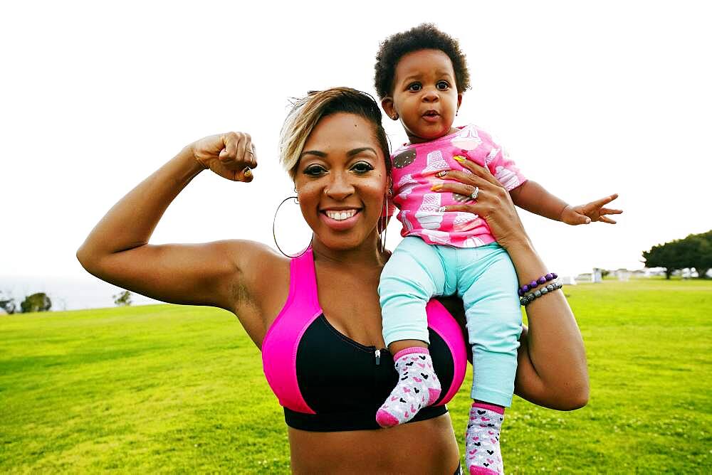 Black woman holding daughter in field