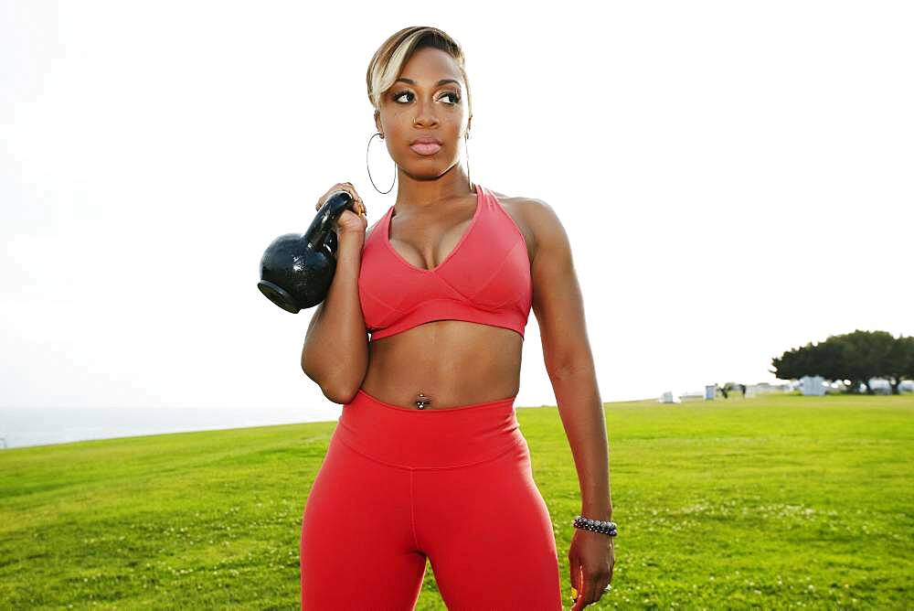 Black woman lifting weights in field