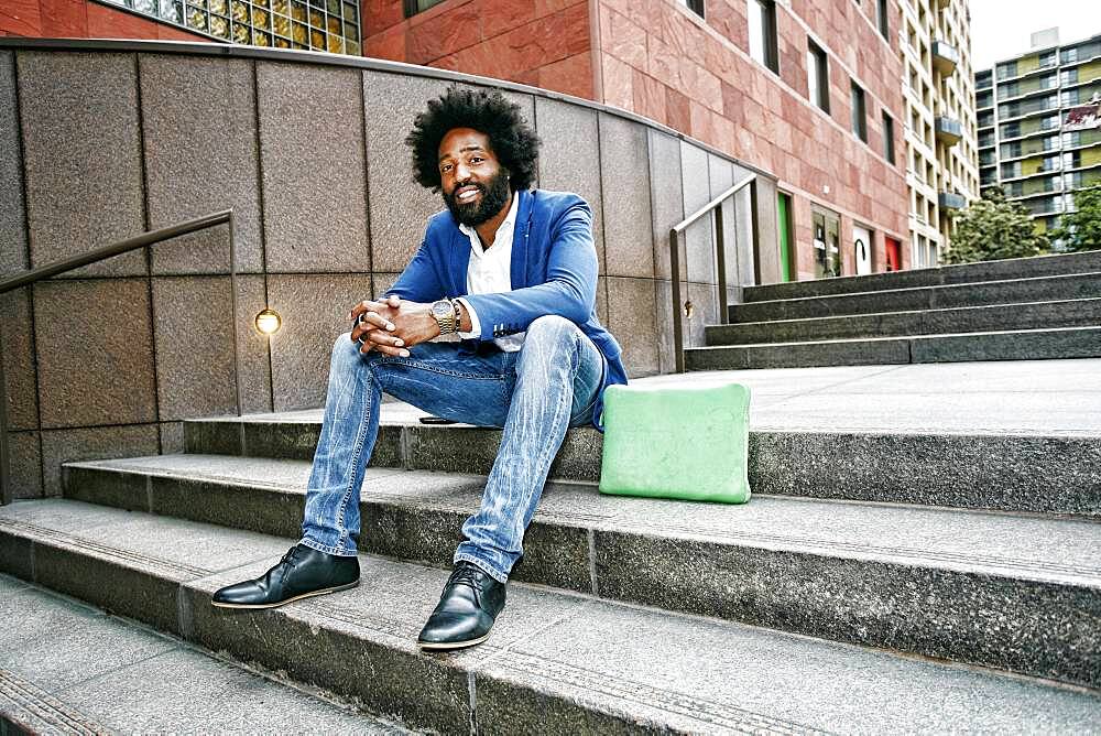 Mixed race businessman sitting on steps