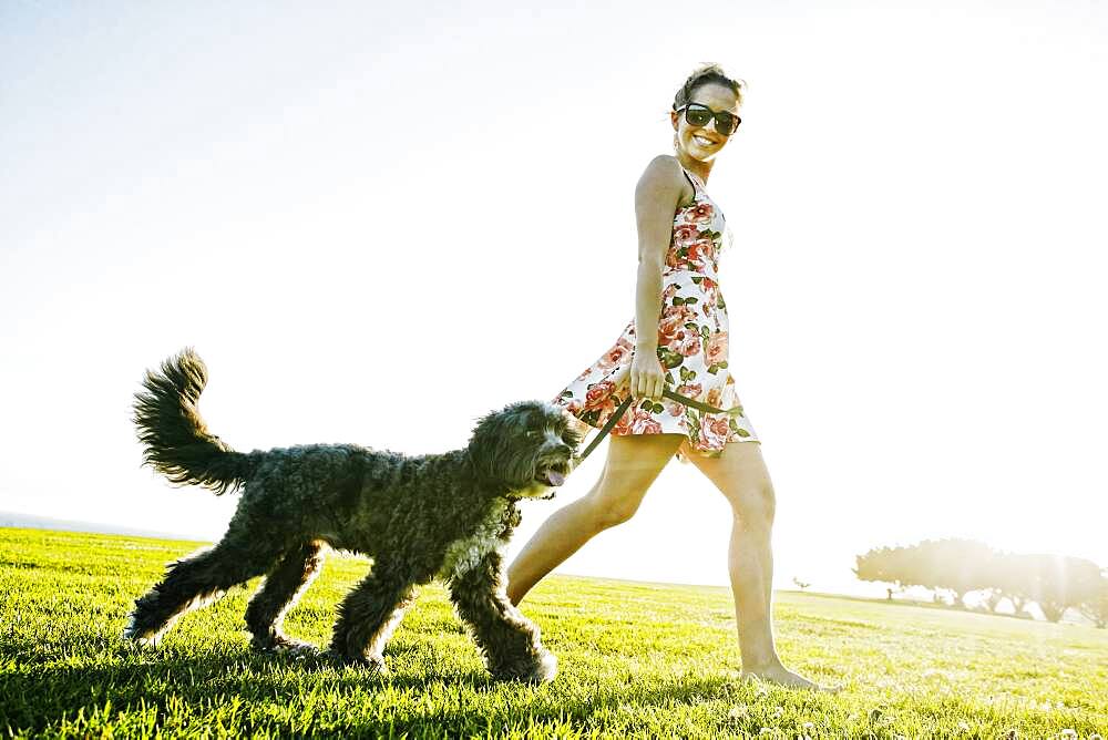 Caucasian woman walking dog in field