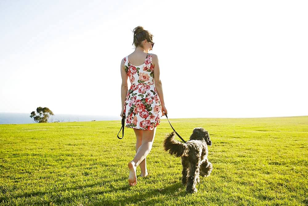 Caucasian woman walking dog in field