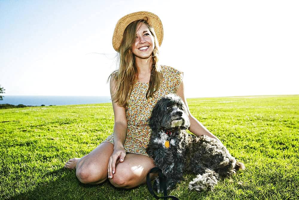 Caucasian woman sitting in field with dog