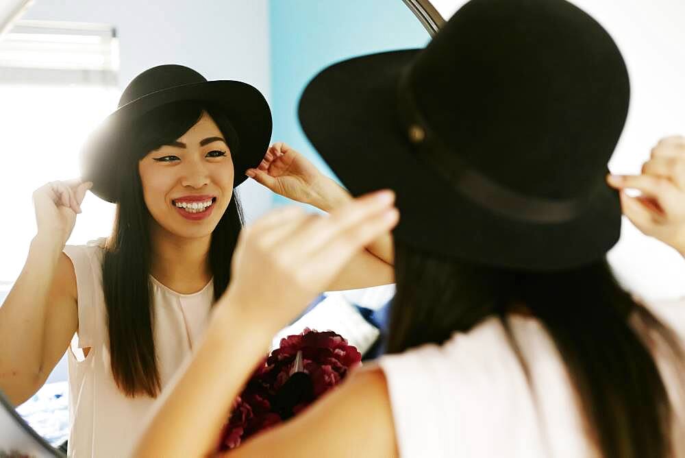 Japanese woman adjusting hat in mirror