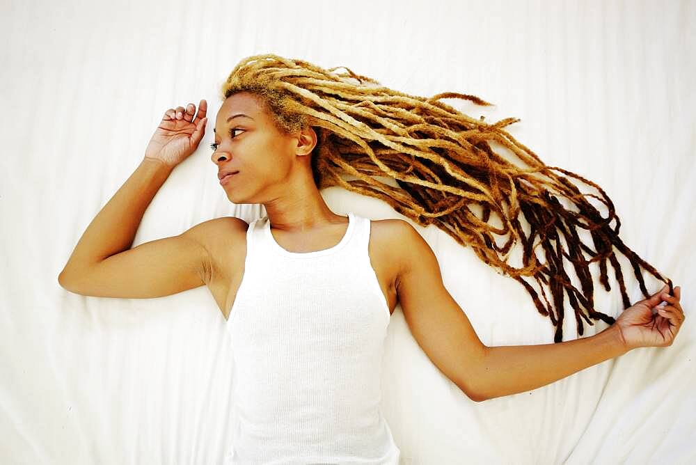 Black woman with dreadlocks laying on bed