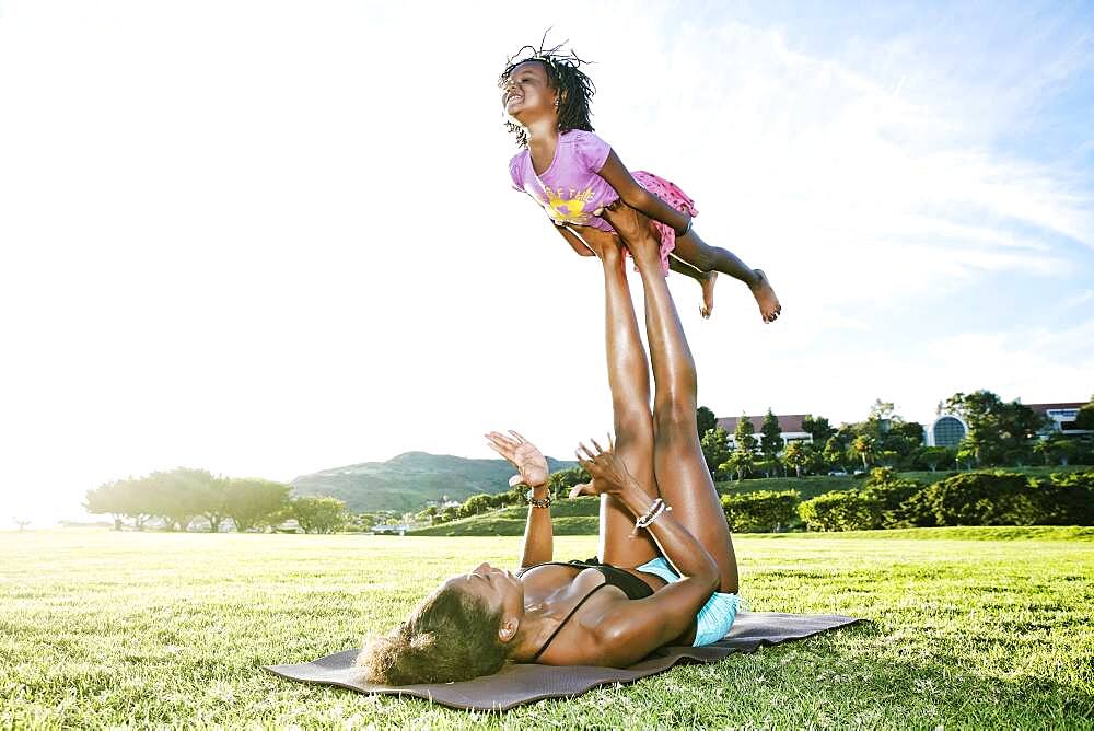 Mother holding daughter with legs in park