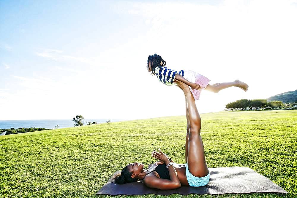 Mother holding daughter with legs in park