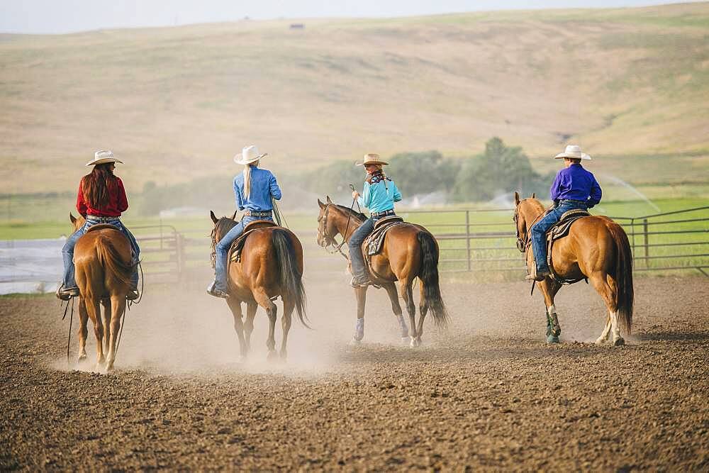 Cowgirls and cowboy riding horses on ranch