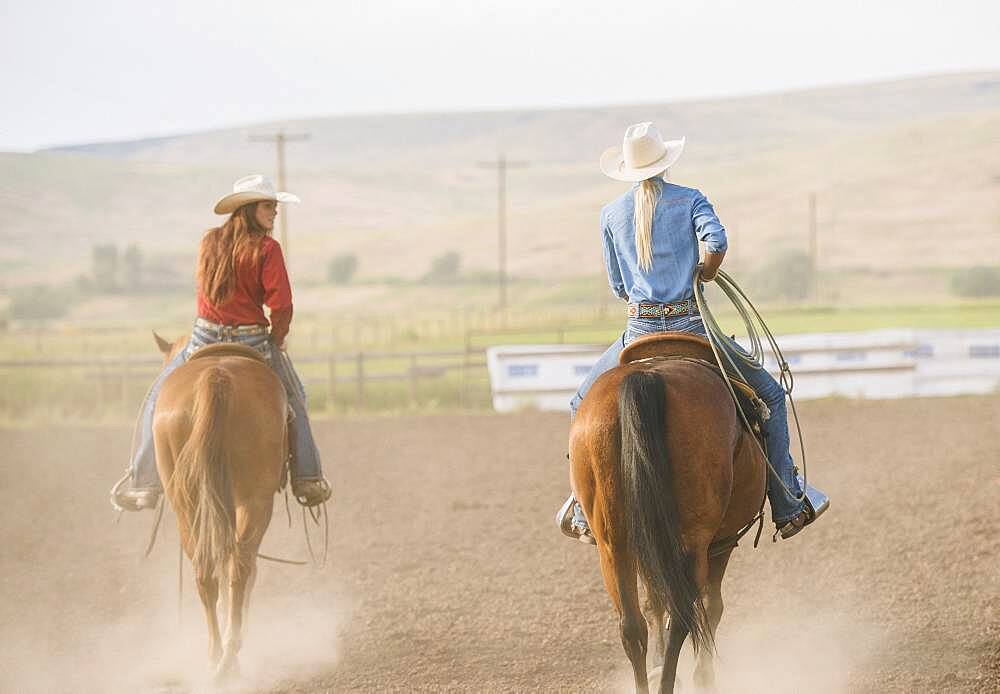 Caucasian cowgirls riding horses on ranch