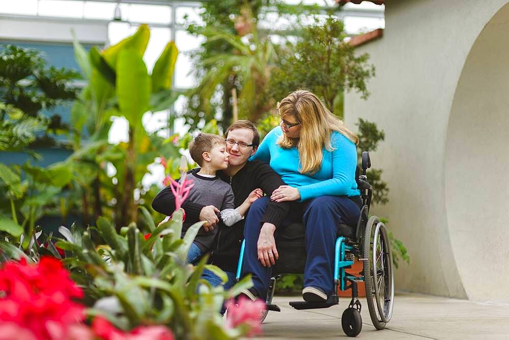 Paraplegic woman and family hugging in garden