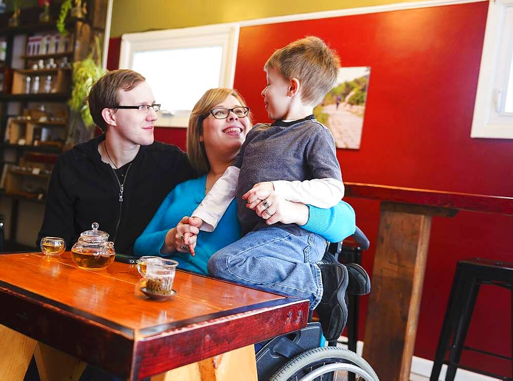 Paraplegic mother holding son in tea shop