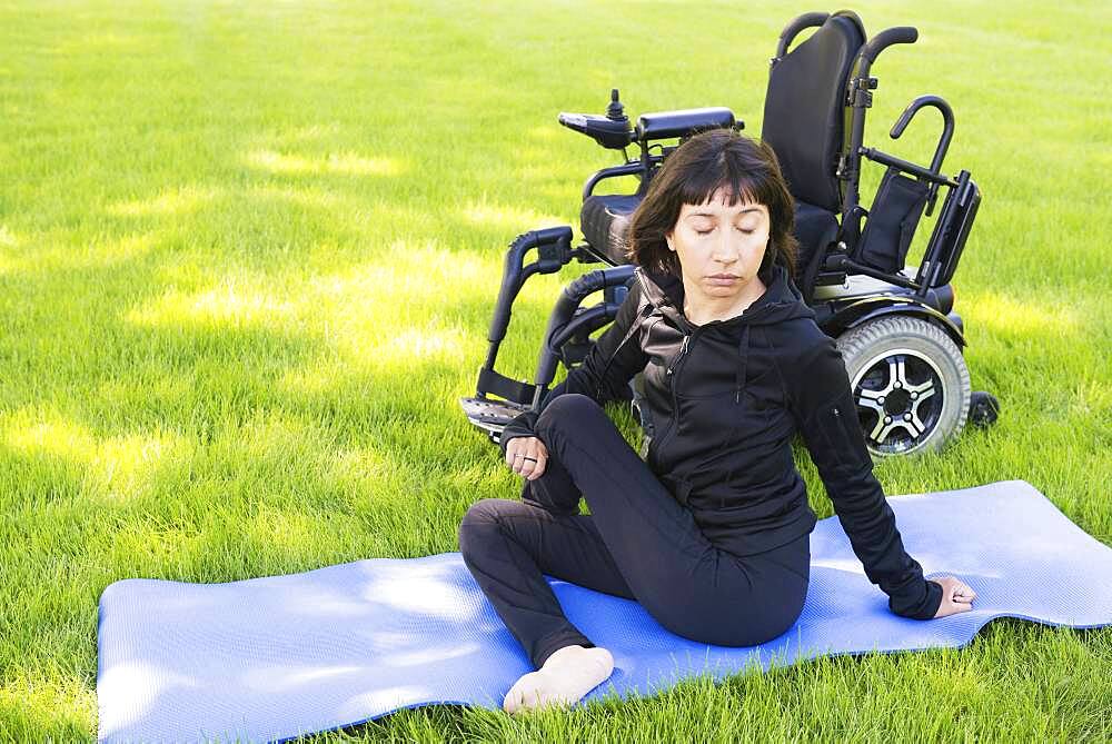 Disabled woman stretching legs in park