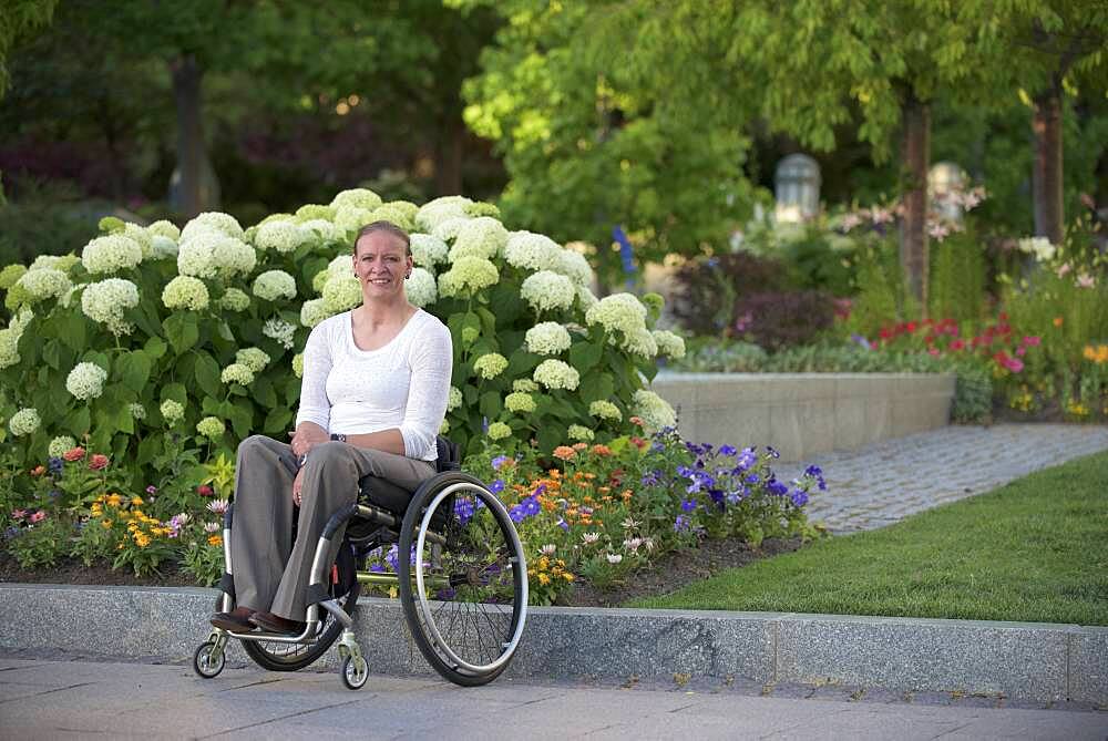 Disabled woman sitting in wheelchair on city street