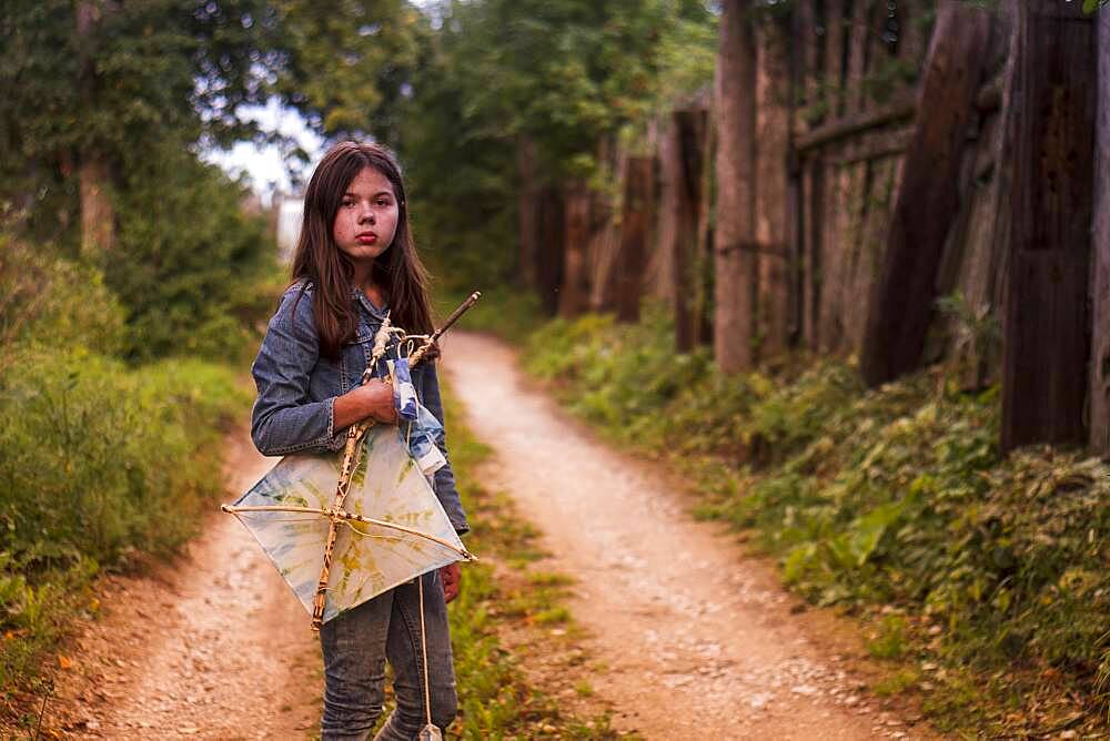 Caucasian teenage girl carrying kite on dirt road