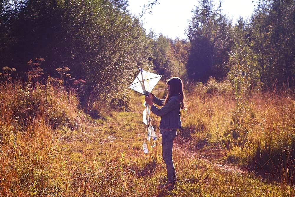 Caucasian teenage girl holding kite in field