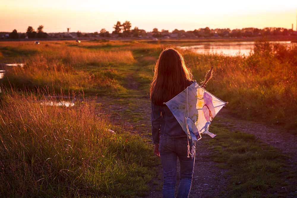 Caucasian teenage girl carrying kite on dirt path