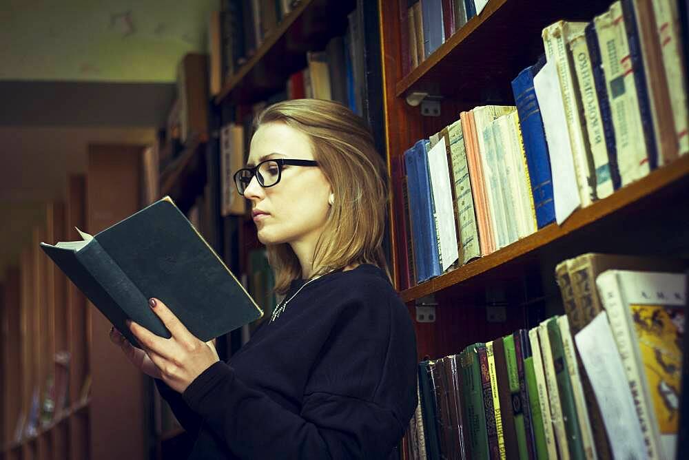 Caucasian woman reading book in library