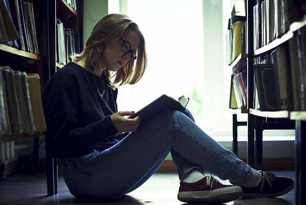 Caucasian woman reading book in library