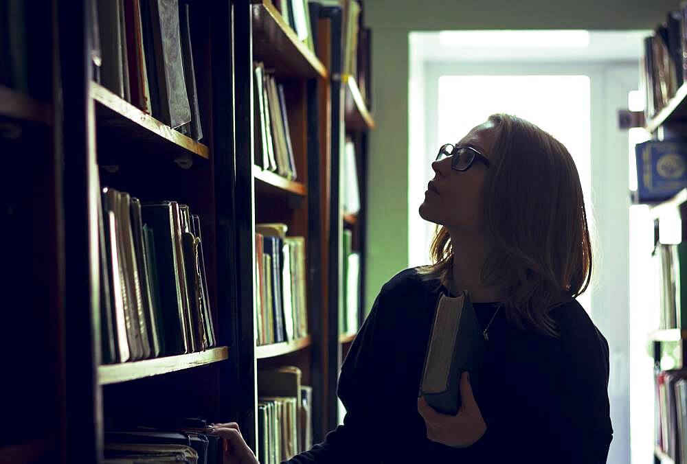 Caucasian woman searching for book in library