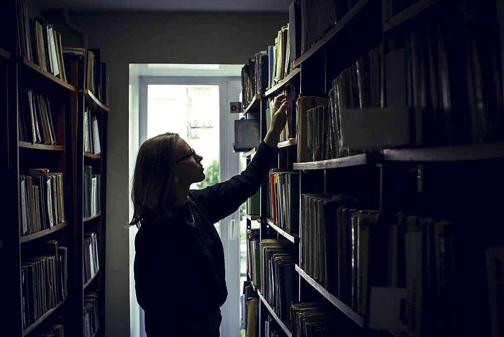 Caucasian woman searching for book in library