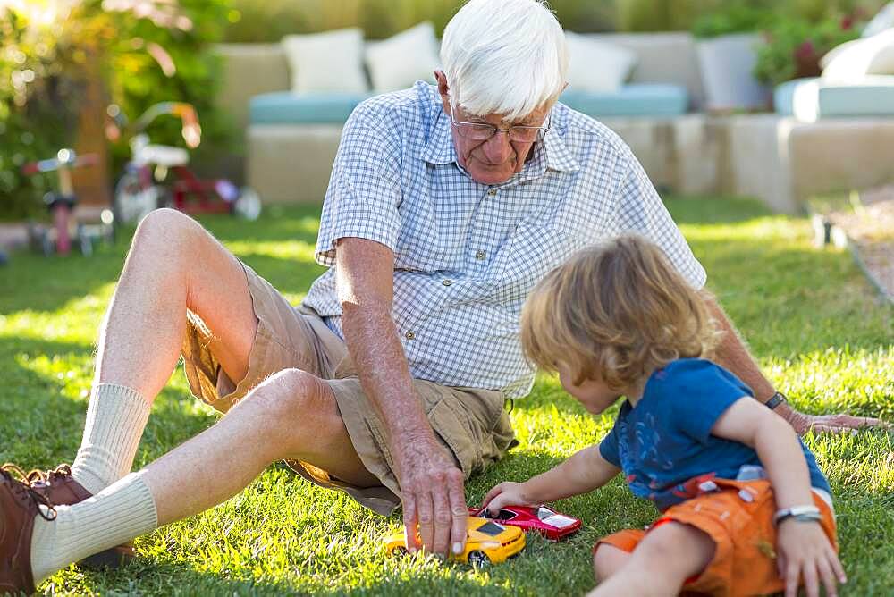 Caucasian grandfather and grandson playing on lawn