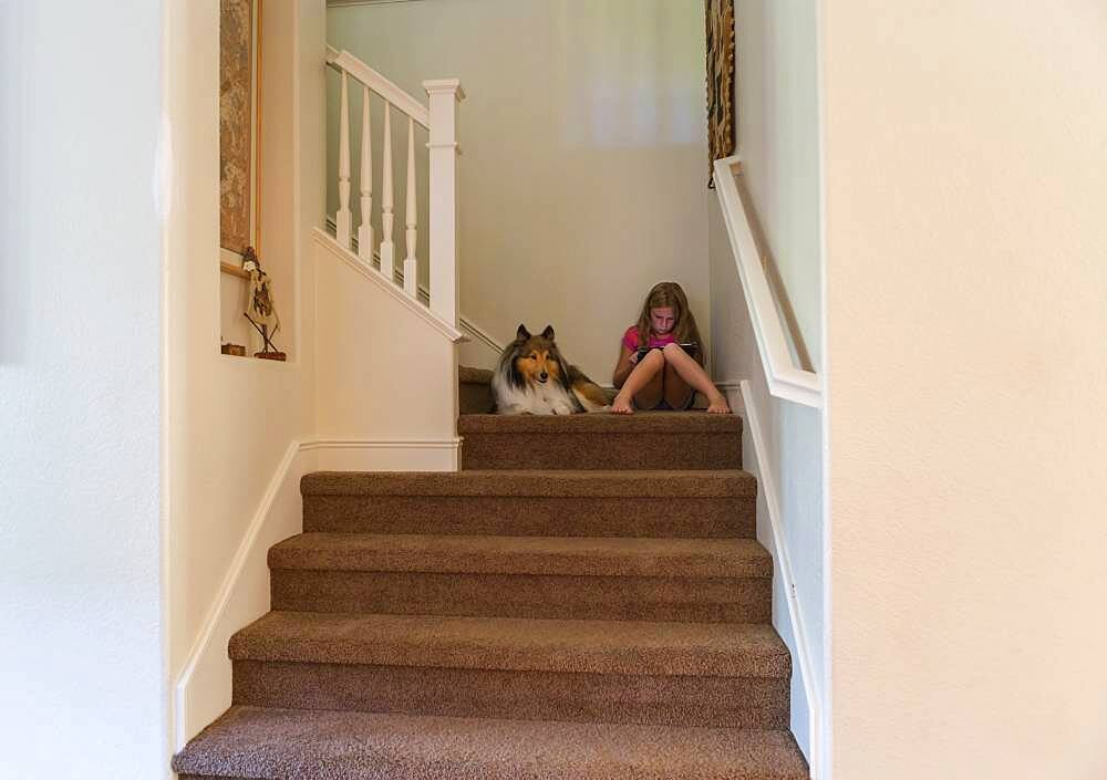 Caucasian girl and dog sitting on stairs