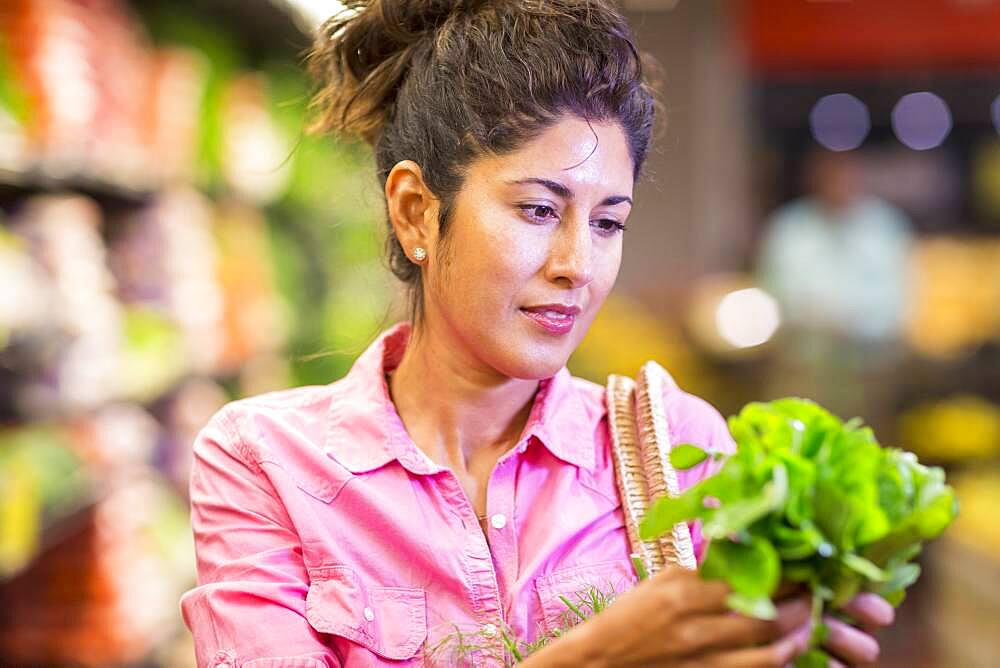 Hispanic woman examining produce at grocery store