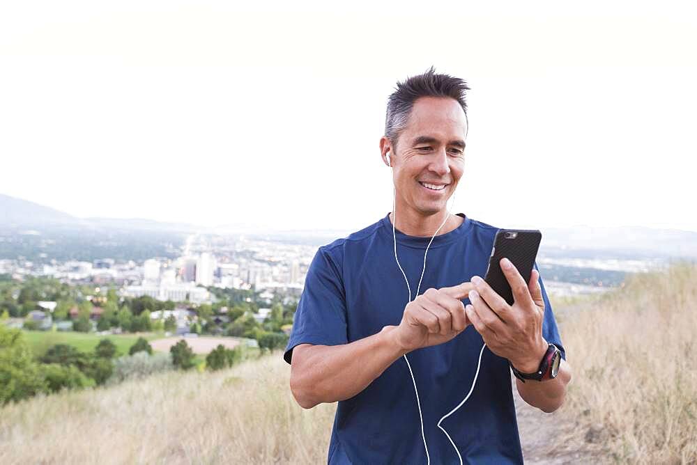 Mixed race man using cell phone on hilltop