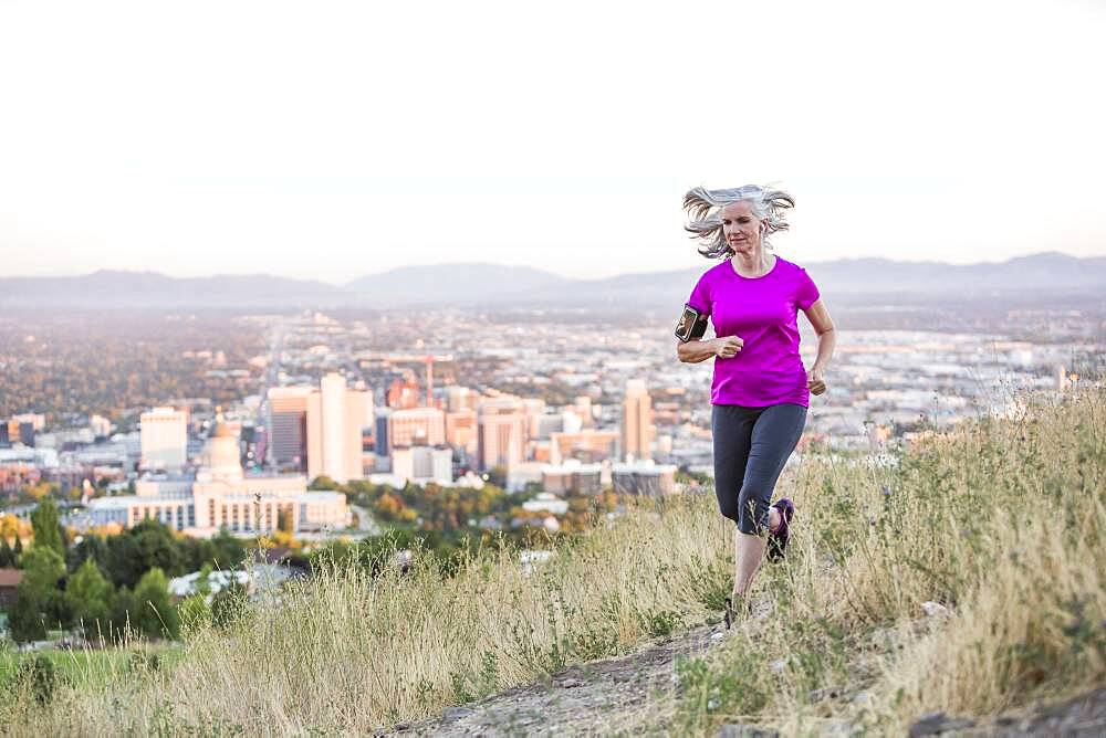 Caucasian woman running on hilltop over Salt Lake City, Utah, United States