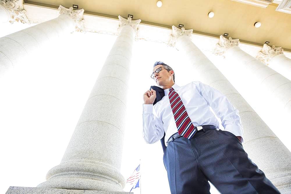 Low angle view of mixed race businessman standing under columns