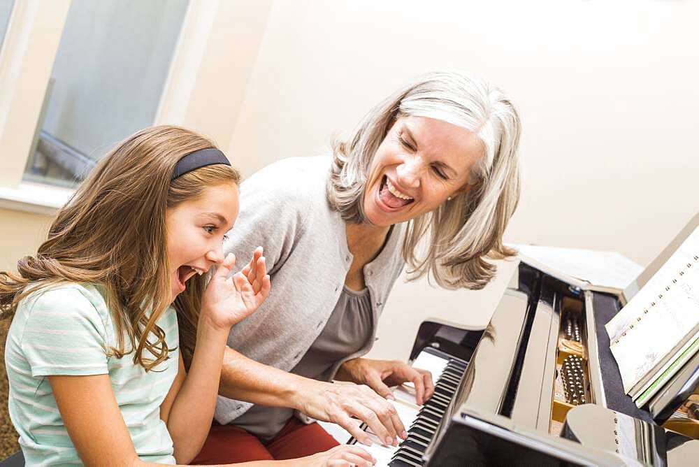 Caucasian grandmother and granddaughter playing piano