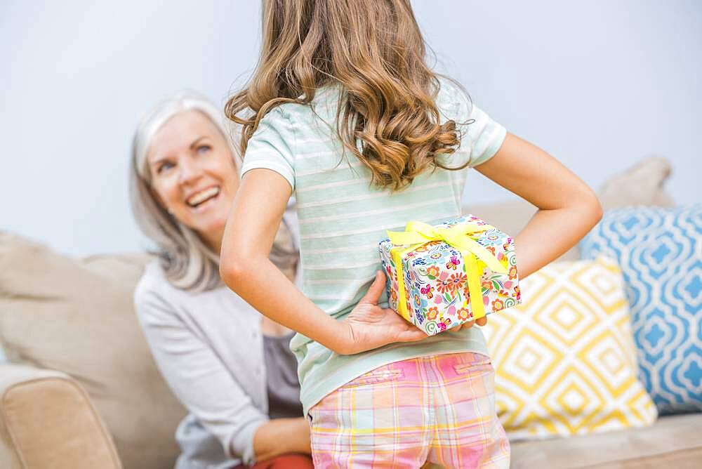 Caucasian girl hiding gift for grandmother behind back