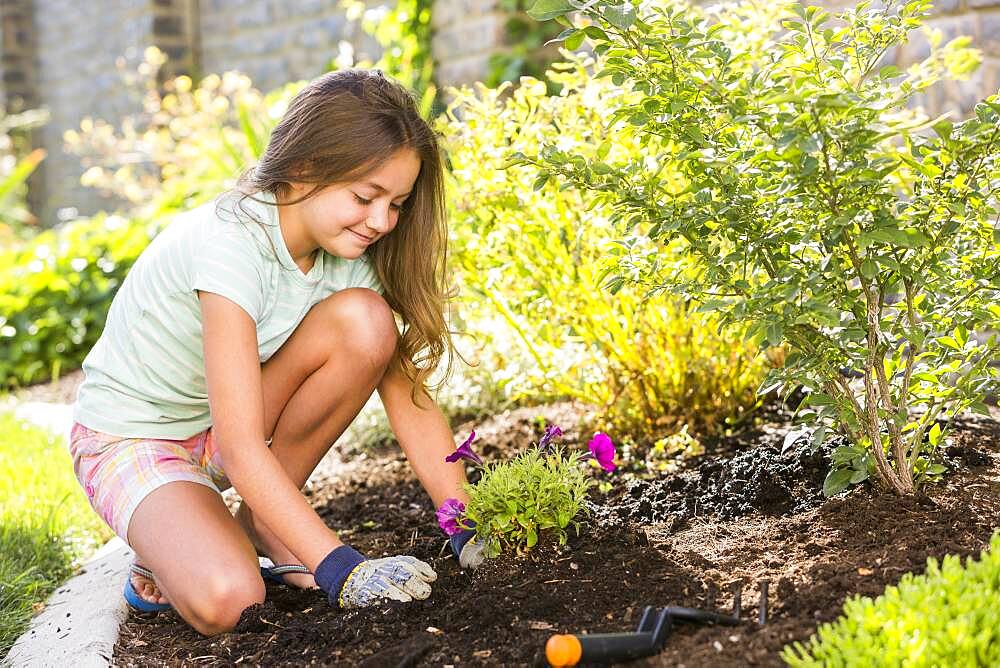 Caucasian girl planting seedling in backyard