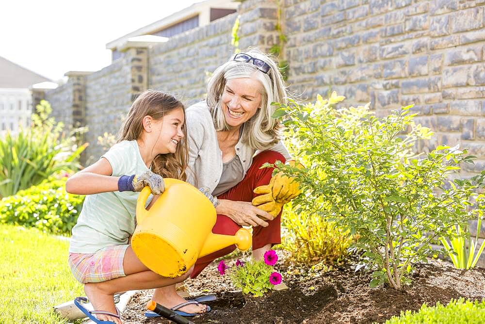 Caucasian grandmother and granddaughter gardening in backyard