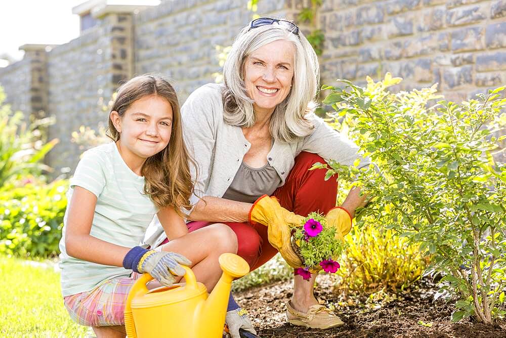 Caucasian grandmother and granddaughter gardening in backyard