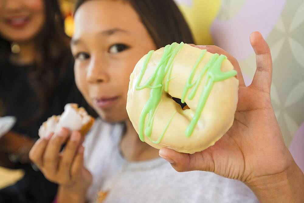 Close up of girl holding donut in bakery