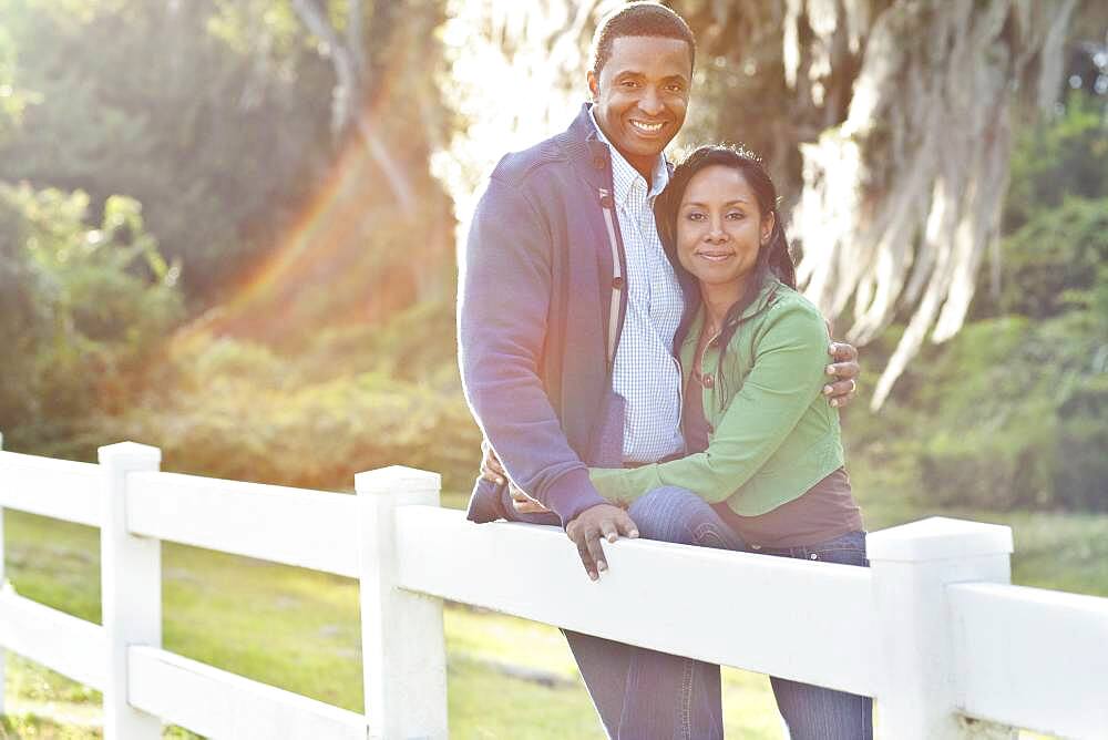 Smiling couple leaning on fence