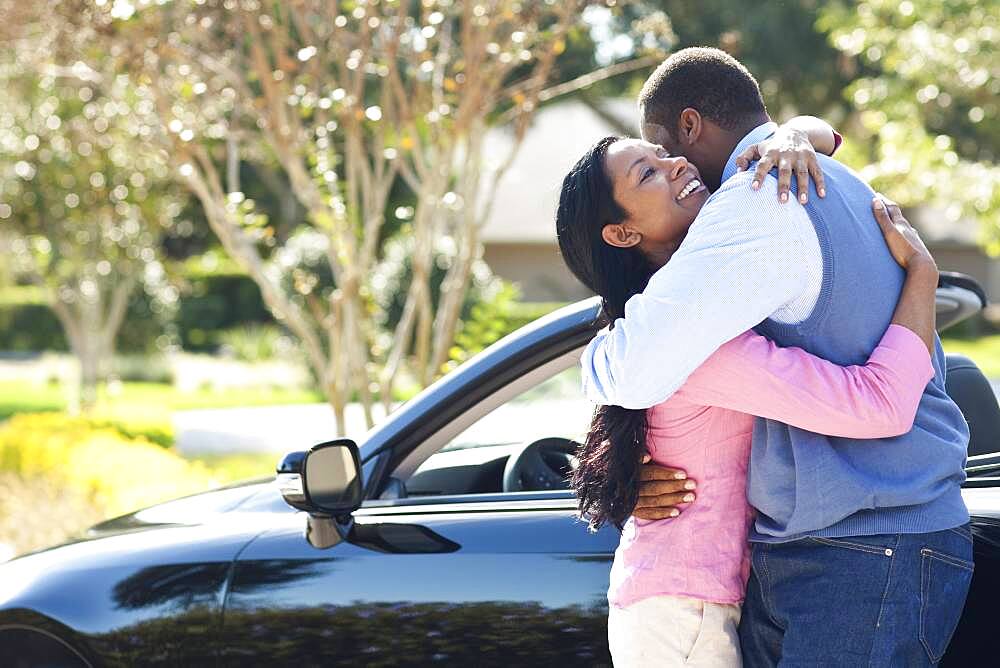 Couple hugging near convertible