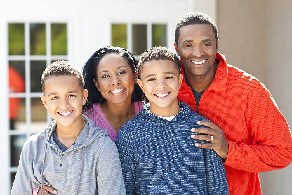 Mother, father and sons smiling outdoors