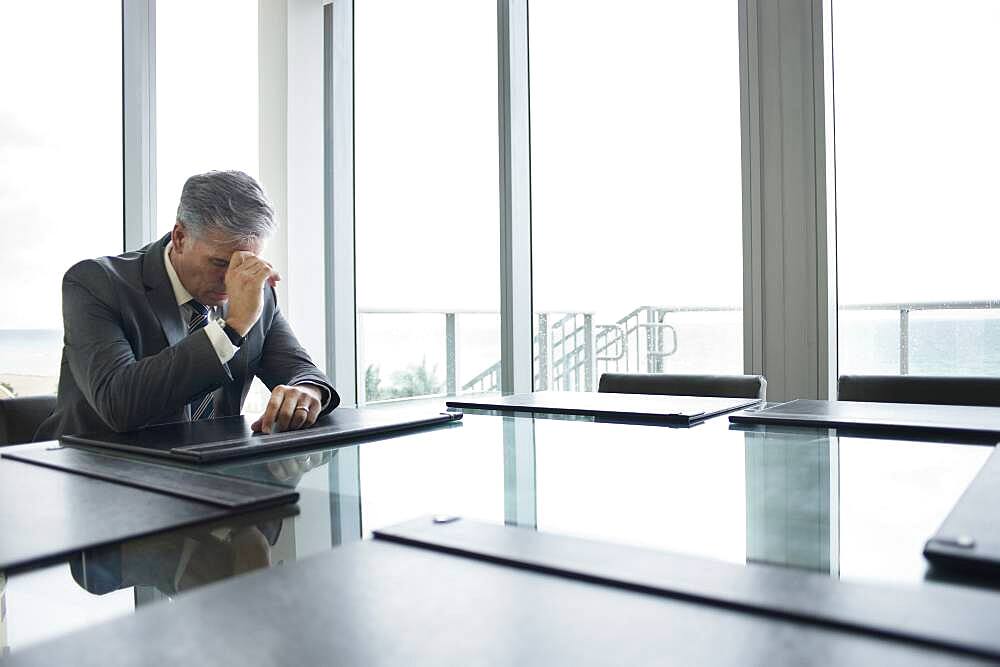 Caucasian businessman brooding at empty conference table