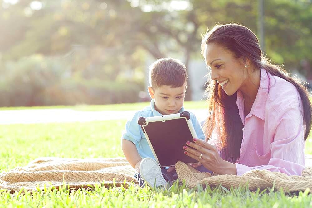 Hispanic mother and son reading in park