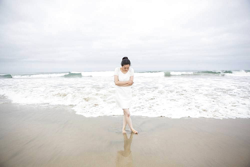 Woman standing near waves on beach